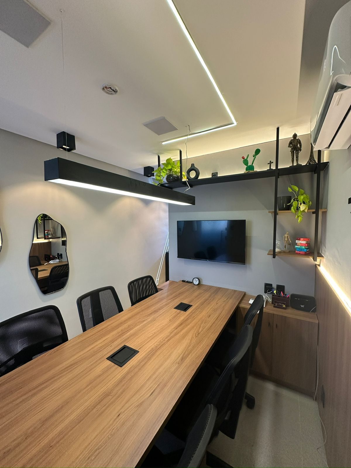 Visão geral da sala, com espelho, mesa e estante
